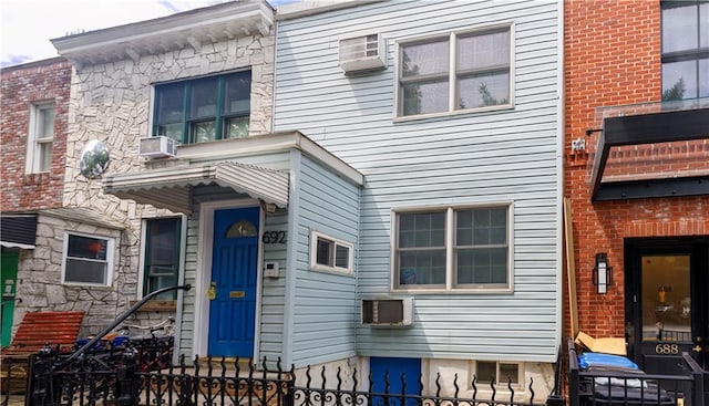 view of front facade with an AC wall unit and cooling unit