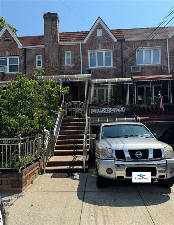 view of front of house featuring brick siding, stairway, a chimney, and fence