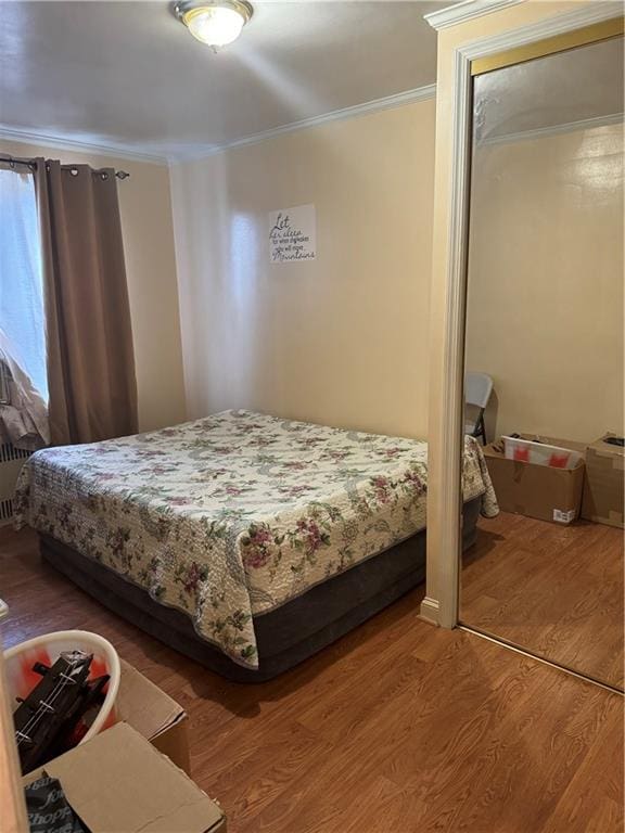 bedroom with crown molding, hardwood / wood-style flooring, and a closet