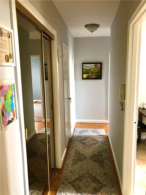 corridor featuring baseboards and wood finished floors