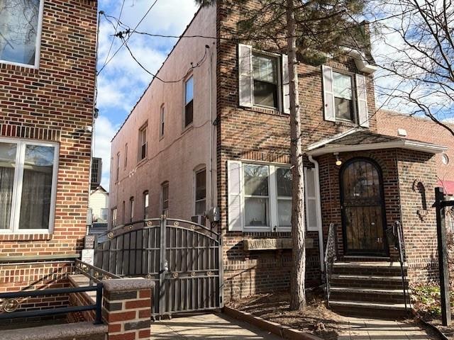 view of front of home with brick siding and a gate