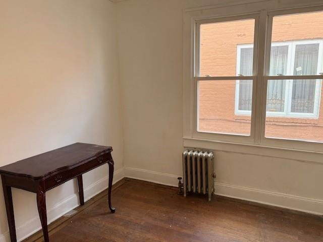 empty room featuring baseboards, plenty of natural light, and radiator heating unit