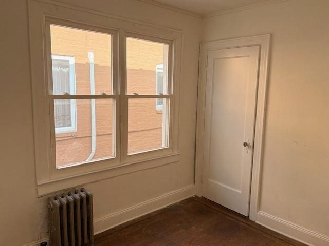 spare room with dark wood finished floors, radiator heating unit, baseboards, and plenty of natural light