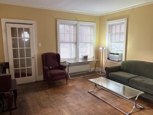 living area with radiator heating unit, cooling unit, dark parquet flooring, and crown molding