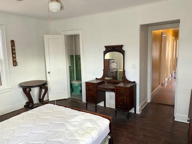 bedroom featuring connected bathroom, baseboards, wood finished floors, and ornamental molding