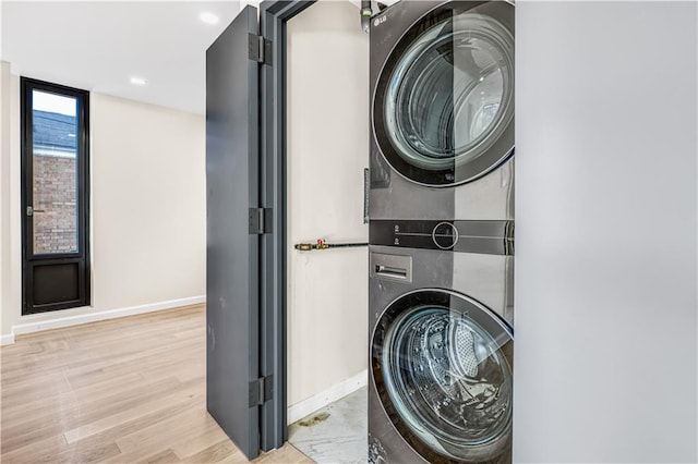 clothes washing area featuring stacked washer / dryer, baseboards, laundry area, recessed lighting, and wood finished floors