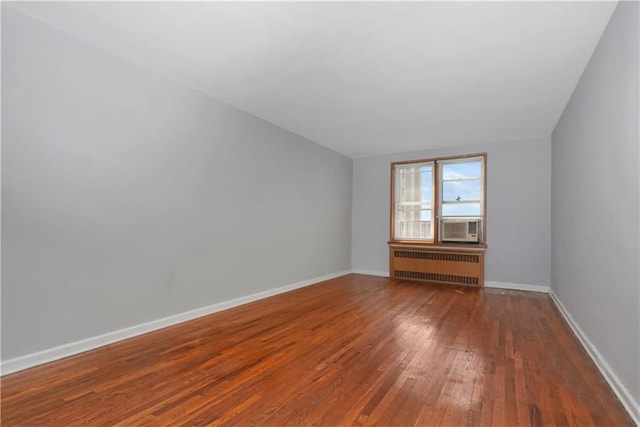 spare room featuring cooling unit, radiator heating unit, and dark hardwood / wood-style floors