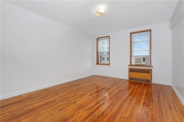 unfurnished room featuring radiator, cooling unit, and light wood-type flooring