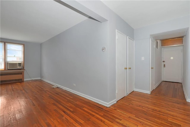 unfurnished room with cooling unit, radiator, and hardwood / wood-style flooring