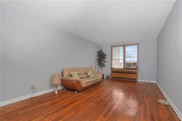 unfurnished room featuring cooling unit, radiator heating unit, and wood-type flooring