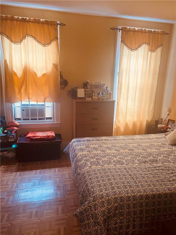 bedroom with dark parquet floors and cooling unit