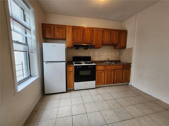 kitchen featuring light tile patterned floors, decorative backsplash, sink, and white appliances