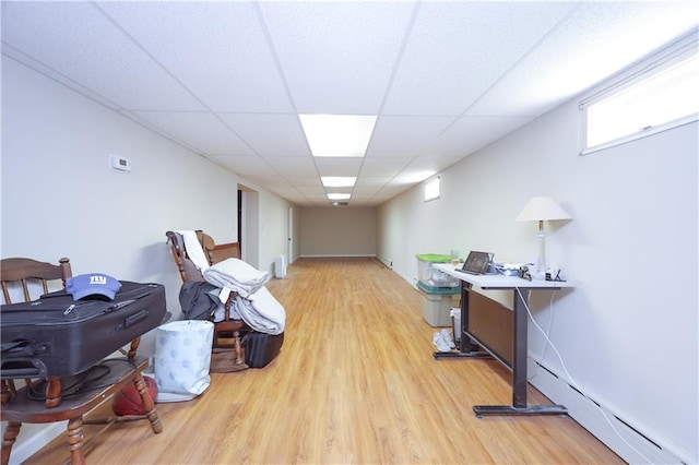 interior space featuring light wood-type flooring, a drop ceiling, and baseboard heating