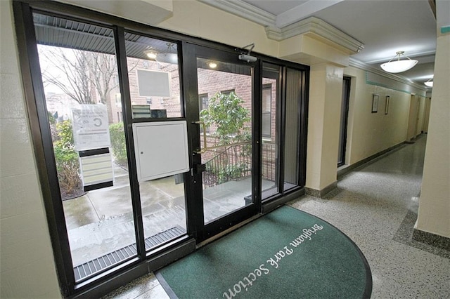 doorway featuring speckled floor, baseboards, plenty of natural light, and crown molding