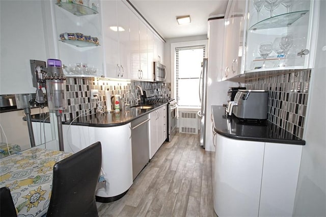 kitchen with tasteful backsplash, dark countertops, appliances with stainless steel finishes, and white cabinets