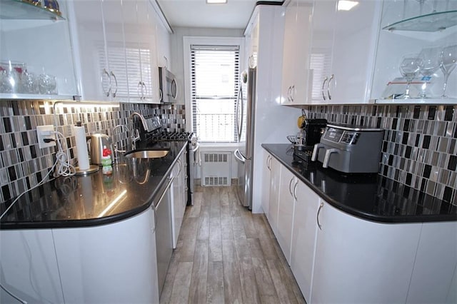 kitchen with appliances with stainless steel finishes, white cabinetry, light wood-type flooring, and tasteful backsplash