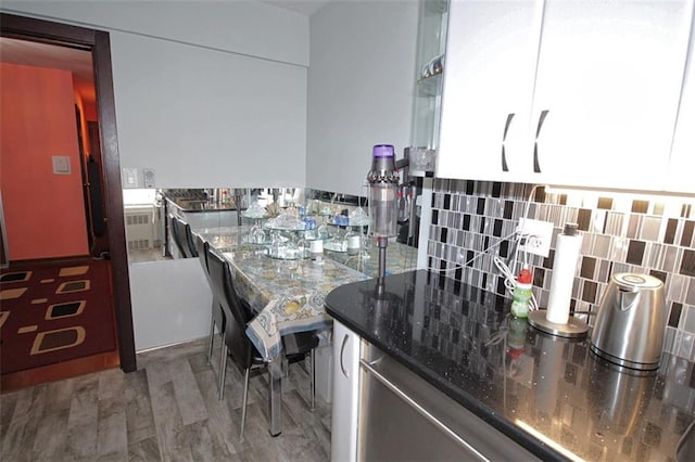 kitchen featuring stone countertops, radiator, tasteful backsplash, and wood finished floors