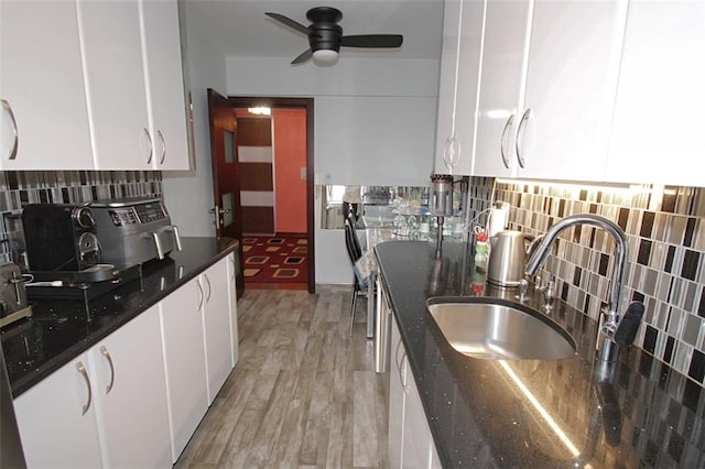 kitchen with a sink, ceiling fan, white cabinets, decorative backsplash, and light wood-type flooring