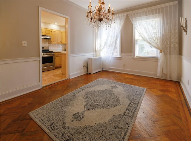 unfurnished dining area featuring a notable chandelier, radiator heating unit, and baseboards