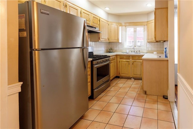 kitchen featuring under cabinet range hood, stainless steel appliances, light brown cabinetry, and a sink