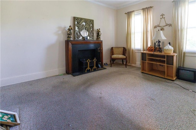 living area featuring a fireplace with flush hearth, plenty of natural light, carpet floors, and ornamental molding