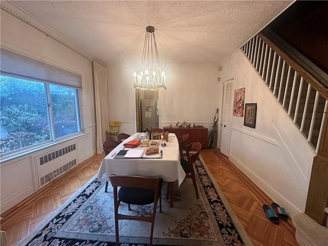 dining area with radiator, parquet floors, a textured ceiling, and a notable chandelier