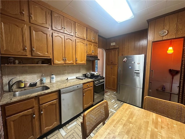 kitchen featuring decorative backsplash, light stone counters, sink, and appliances with stainless steel finishes