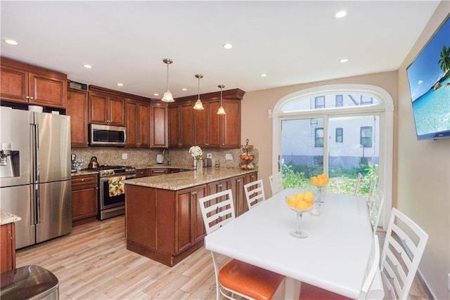 kitchen featuring hanging light fixtures, light hardwood / wood-style flooring, tasteful backsplash, kitchen peninsula, and stainless steel appliances