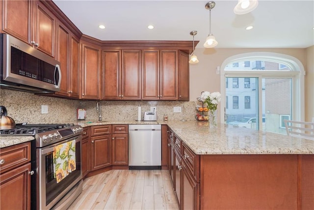 kitchen featuring pendant lighting, tasteful backsplash, light hardwood / wood-style floors, kitchen peninsula, and stainless steel appliances