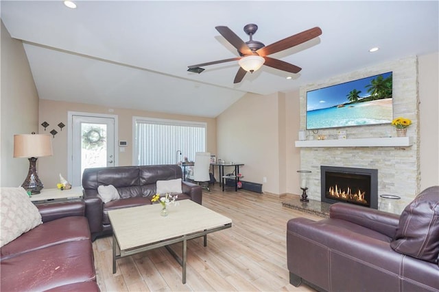 living room featuring ceiling fan, light hardwood / wood-style floors, a fireplace, and vaulted ceiling