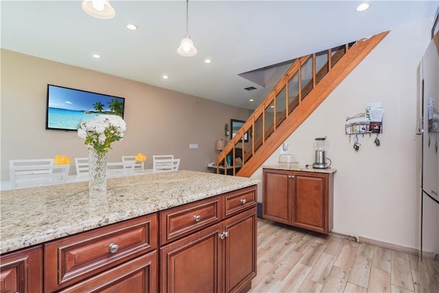 kitchen featuring pendant lighting, light stone counters, and light hardwood / wood-style flooring