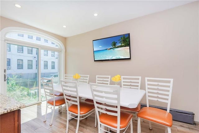 dining space featuring plenty of natural light, light hardwood / wood-style floors, and a baseboard heating unit