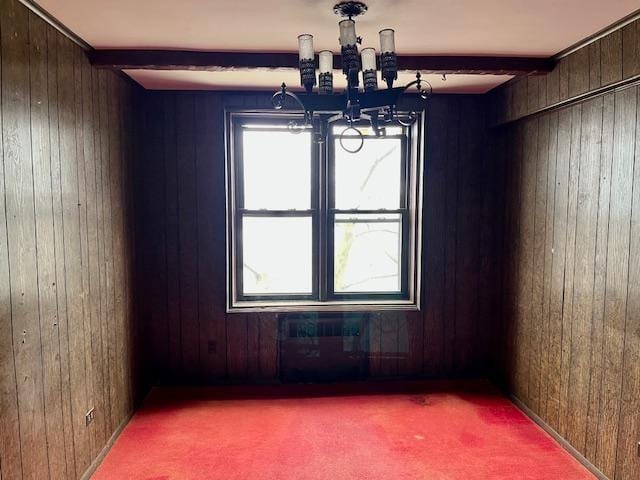 unfurnished dining area with carpet floors, beamed ceiling, and wood walls