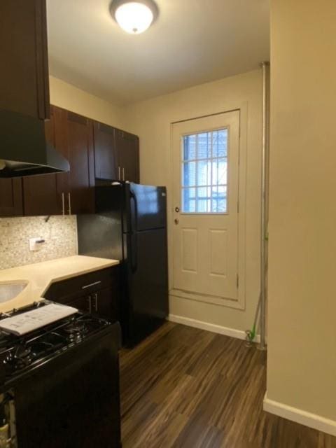 kitchen featuring dark brown cabinetry, tasteful backsplash, black fridge, stove, and dark wood-type flooring