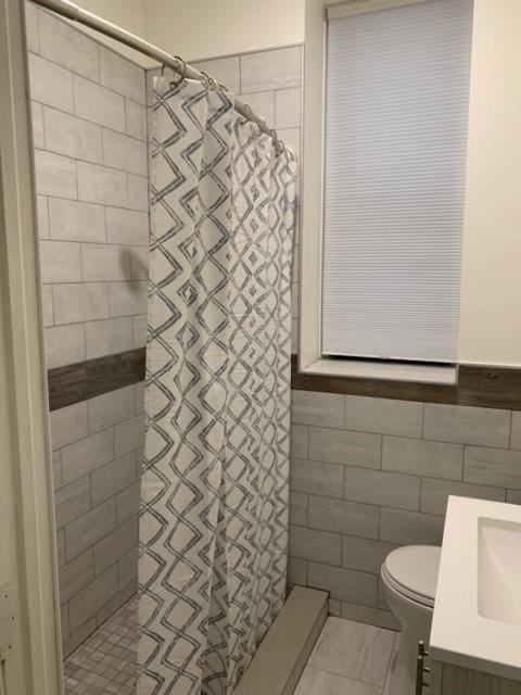 bathroom featuring tile patterned floors, toilet, vanity, and tile walls