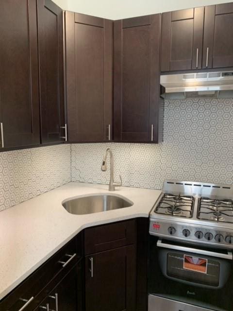 kitchen featuring sink, dark brown cabinetry, range with gas cooktop, and decorative backsplash