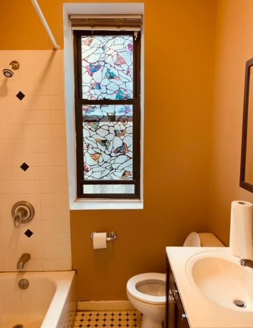 full bathroom with tile patterned flooring, vanity, tiled shower / bath combo, and toilet