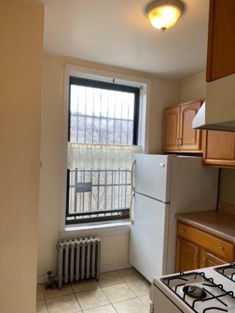 kitchen with light tile patterned floors, range, and radiator heating unit