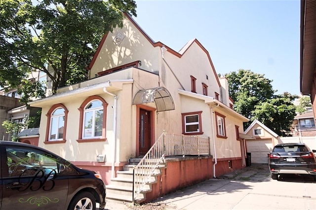 226 W End Ave, New York, NY 11235 - view of front of property with a garage, an outdoor structure, stucco siding, and concrete driveway