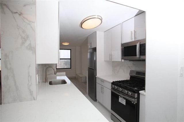 kitchen with tasteful backsplash, white cabinetry, sink, and appliances with stainless steel finishes