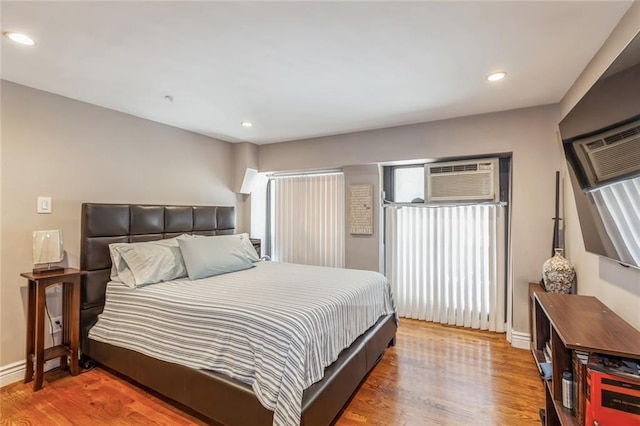 bedroom featuring hardwood / wood-style flooring and a wall unit AC