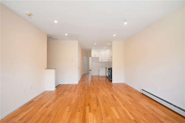 unfurnished living room with a baseboard heating unit and light hardwood / wood-style floors