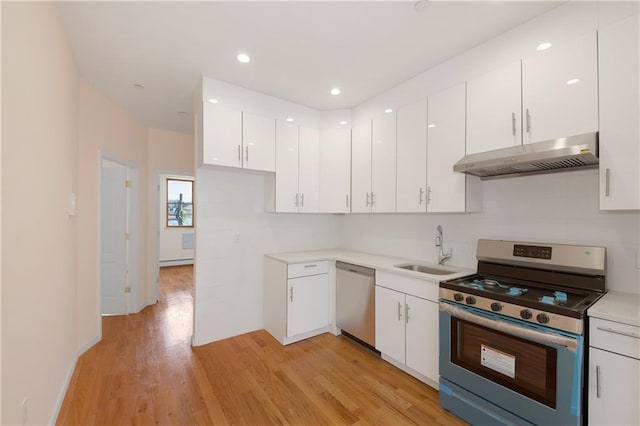 kitchen featuring under cabinet range hood, light wood-type flooring, white cabinets, stainless steel appliances, and a sink