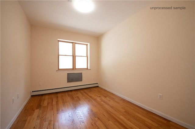 empty room with baseboards, baseboard heating, and light wood-style flooring