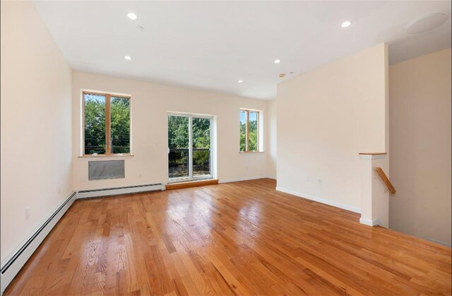 unfurnished living room with a baseboard radiator and light wood-type flooring