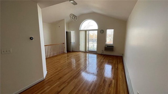 spare room featuring an AC wall unit, wood-type flooring, lofted ceiling, and a baseboard radiator