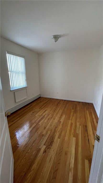 unfurnished room with a baseboard radiator and hardwood / wood-style floors