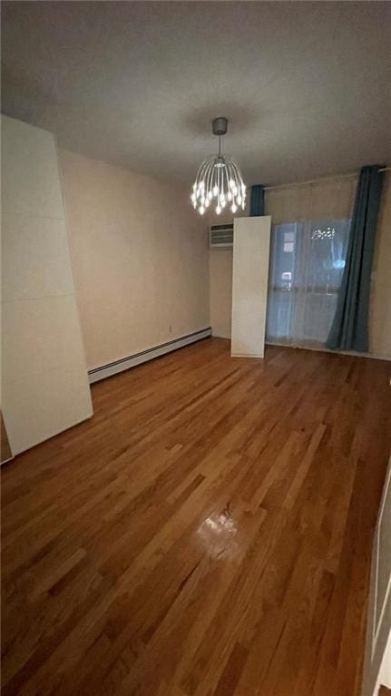 empty room featuring a baseboard radiator, hardwood / wood-style floors, a chandelier, and an AC wall unit