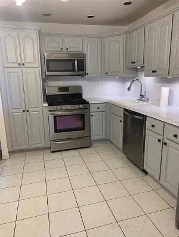 kitchen with appliances with stainless steel finishes, sink, gray cabinetry, and light tile patterned floors