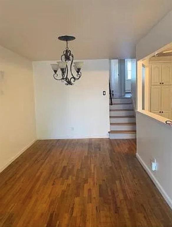 unfurnished dining area with a notable chandelier and dark wood-type flooring